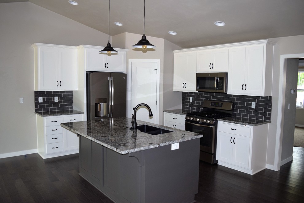 Example of a mountain style kitchen design with white cabinets, stainless steel appliances and an island