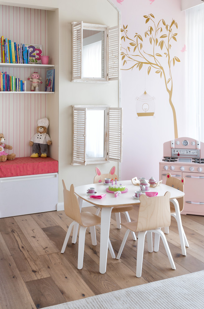 This is an example of a mid-sized beach style kids' room for girls in Miami with pink walls and light hardwood floors.