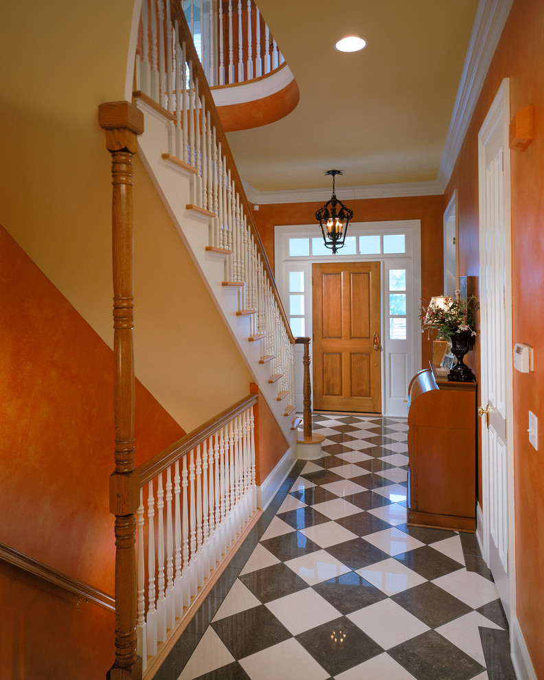 This is an example of a traditional entry hall in New York with orange walls and multi-coloured floor.