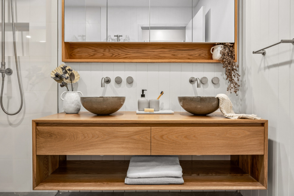 This is an example of a mid-sized contemporary master bathroom in Central Coast with light wood cabinets, an open shower, a vessel sink, an open shower, a niche, a double vanity and a floating vanity.