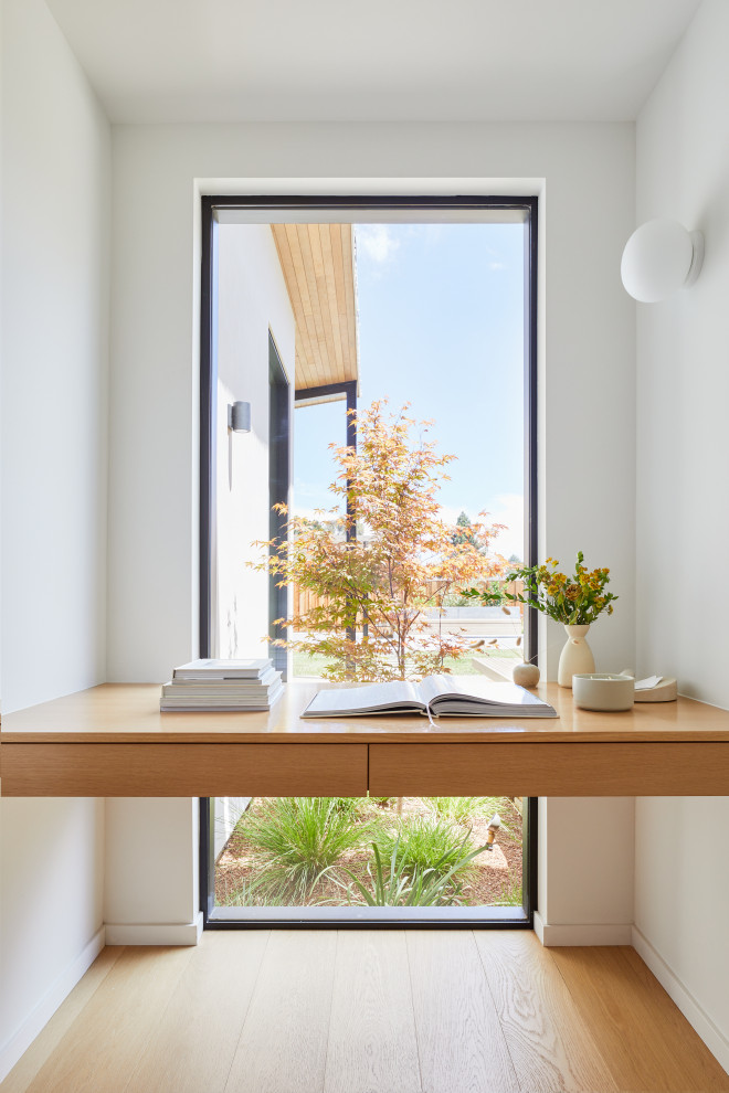 Kleines Modernes Arbeitszimmer mit weißer Wandfarbe, hellem Holzboden, Einbau-Schreibtisch und braunem Boden in San Francisco