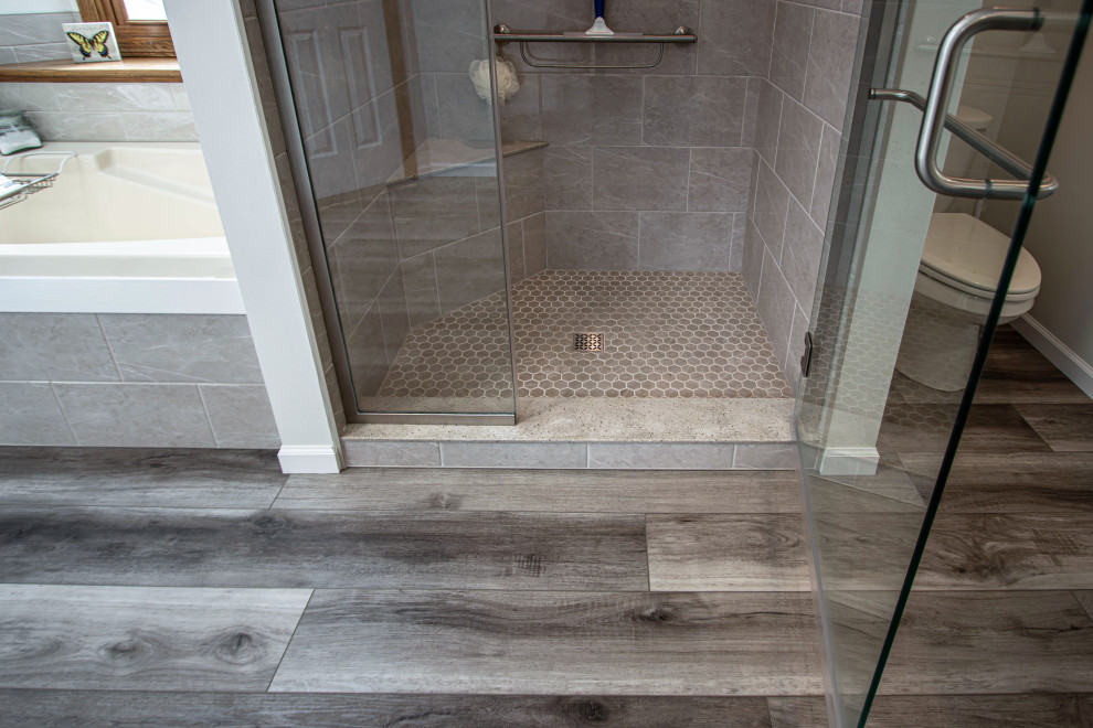 Idéer för ett mellanstort klassiskt grå en-suite badrum, med skåp i shakerstil, grå skåp, en dusch i en alkov, grå kakel, vinylgolv, bänkskiva i akrylsten, brunt golv och dusch med gångjärnsdörr