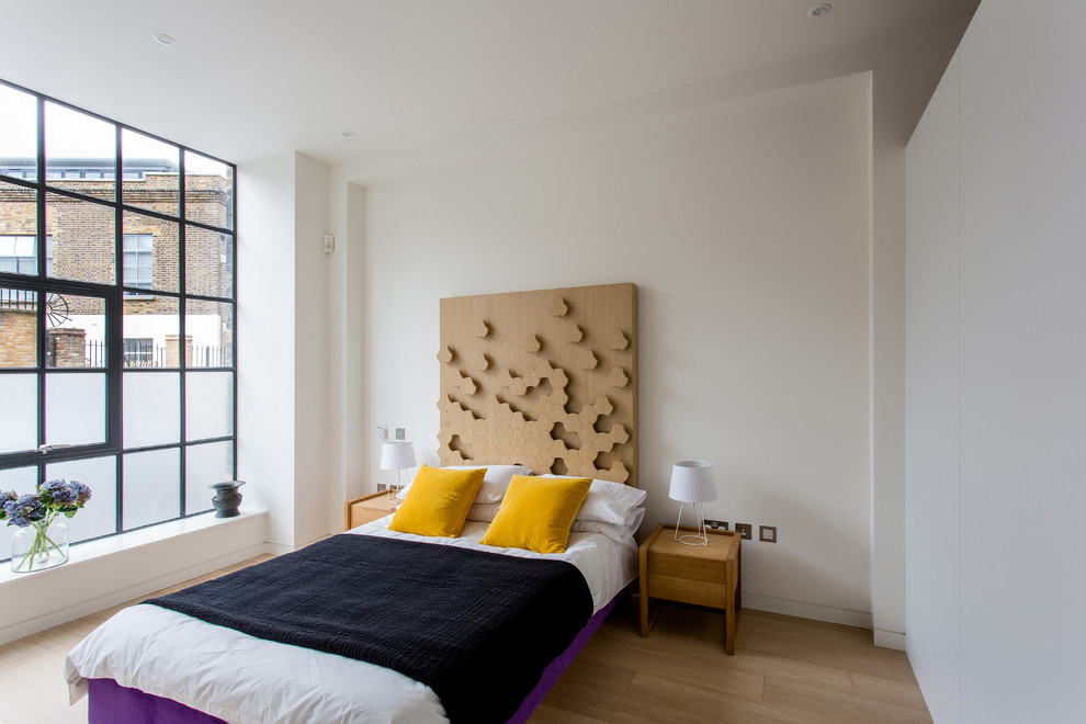 Design ideas for an industrial bedroom in London with white walls and light hardwood floors.