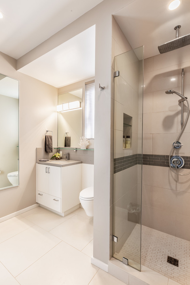 This is an example of a large modern 3/4 bathroom in Hawaii with flat-panel cabinets, white cabinets, an alcove shower, a wall-mount toilet, beige tile, porcelain tile, beige walls, porcelain floors, an undermount sink, beige floor and a hinged shower door.