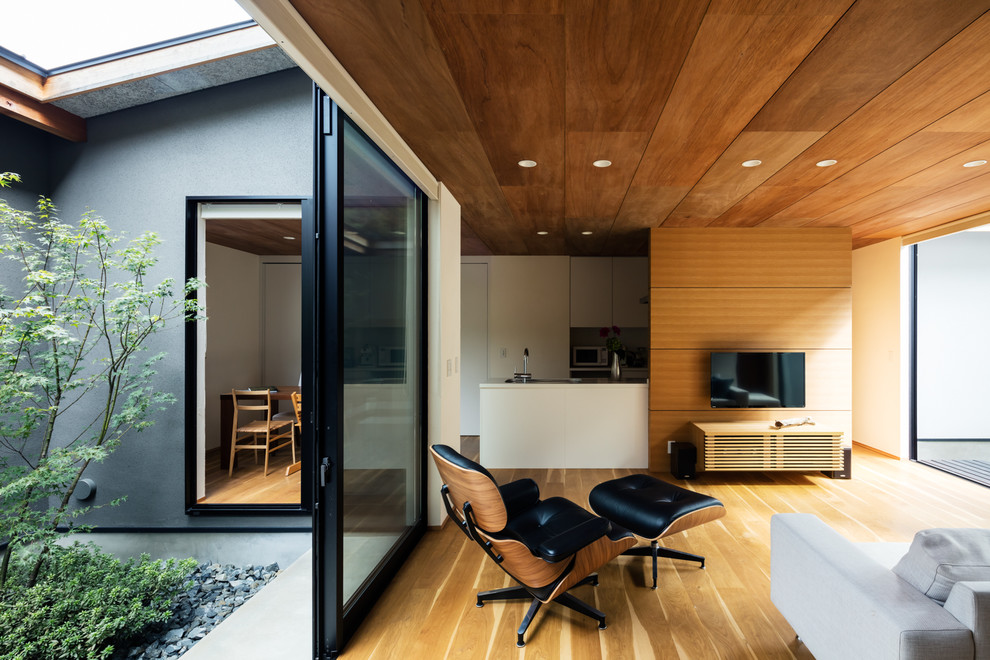 Photo of a contemporary open concept living room in Kyoto with white walls, medium hardwood floors, a wall-mounted tv and brown floor.
