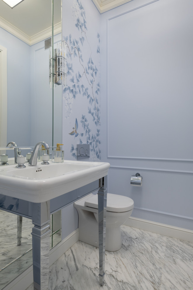 Photo of a small transitional powder room in Moscow with a wall-mount toilet, blue walls, marble floors, a console sink, white floor, a freestanding vanity and wallpaper.
