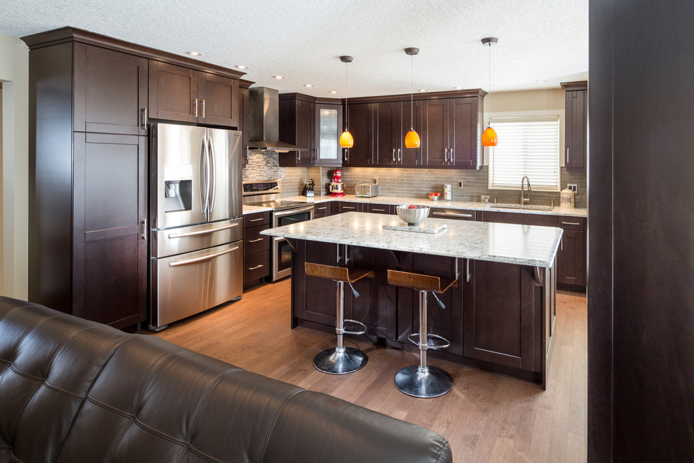 Example of a mid-sized trendy light wood floor eat-in kitchen design with an undermount sink, recessed-panel cabinets, dark wood cabinets, quartzite countertops, gray backsplash, subway tile backsplash, stainless steel appliances and an island