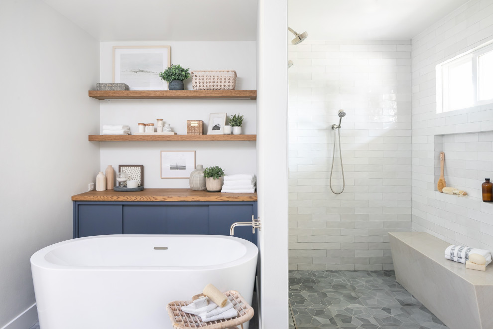 Bild på ett vintage badrum, med ett fristående badkar, vit kakel, vita väggar, grått golv och med dusch som är öppen