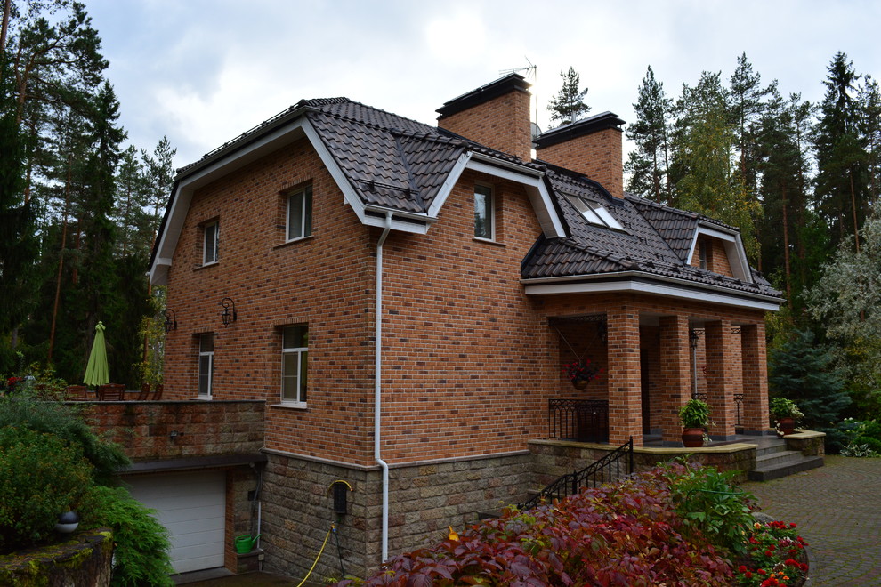 This is an example of a mid-sized contemporary two-storey brick brown house exterior in Saint Petersburg with a clipped gable roof and a tile roof.