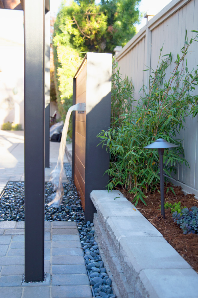 Small contemporary courtyard patio in San Luis Obispo with a water feature, concrete pavers and a pergola.