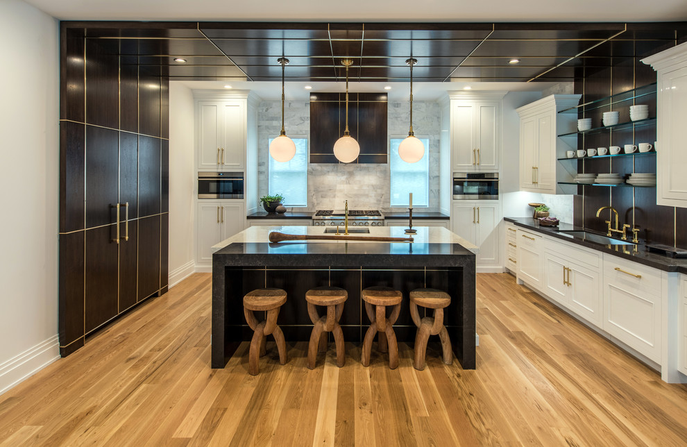 Contemporary u-shaped kitchen in New York with an undermount sink, shaker cabinets, black cabinets, grey splashback, panelled appliances, medium hardwood floors, with island and brown floor.