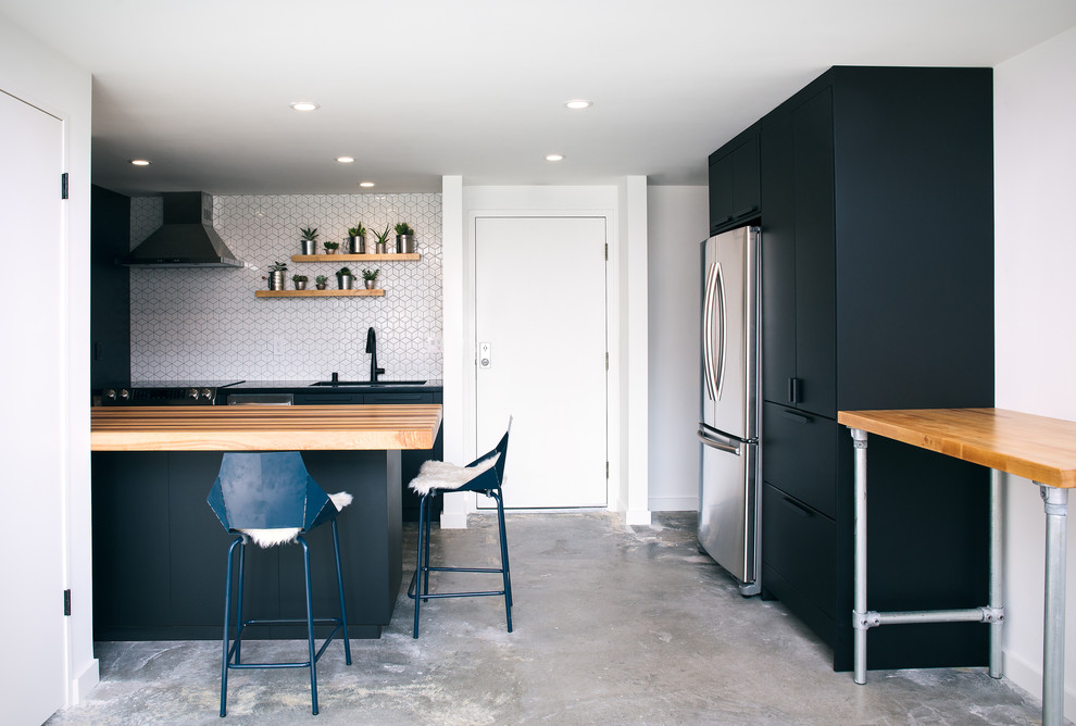 Photo of a small contemporary galley eat-in kitchen in San Francisco with an undermount sink, flat-panel cabinets, black cabinets, wood benchtops, white splashback, ceramic splashback, stainless steel appliances, concrete floors, with island, grey floor and multi-coloured benchtop.