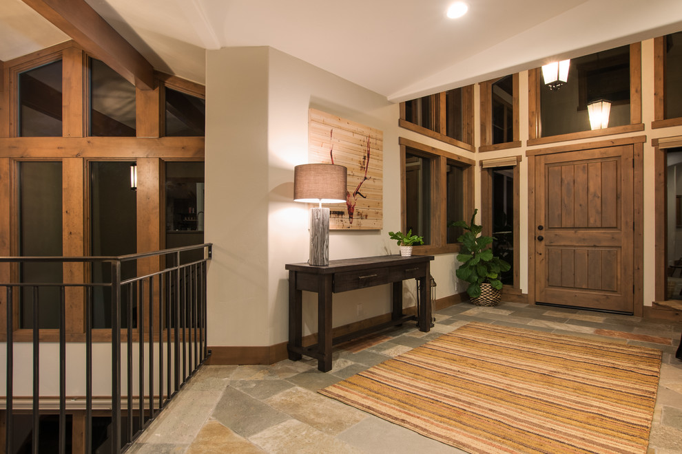 Mid-sized mountain style slate floor front door photo with beige walls and a dark wood front door
