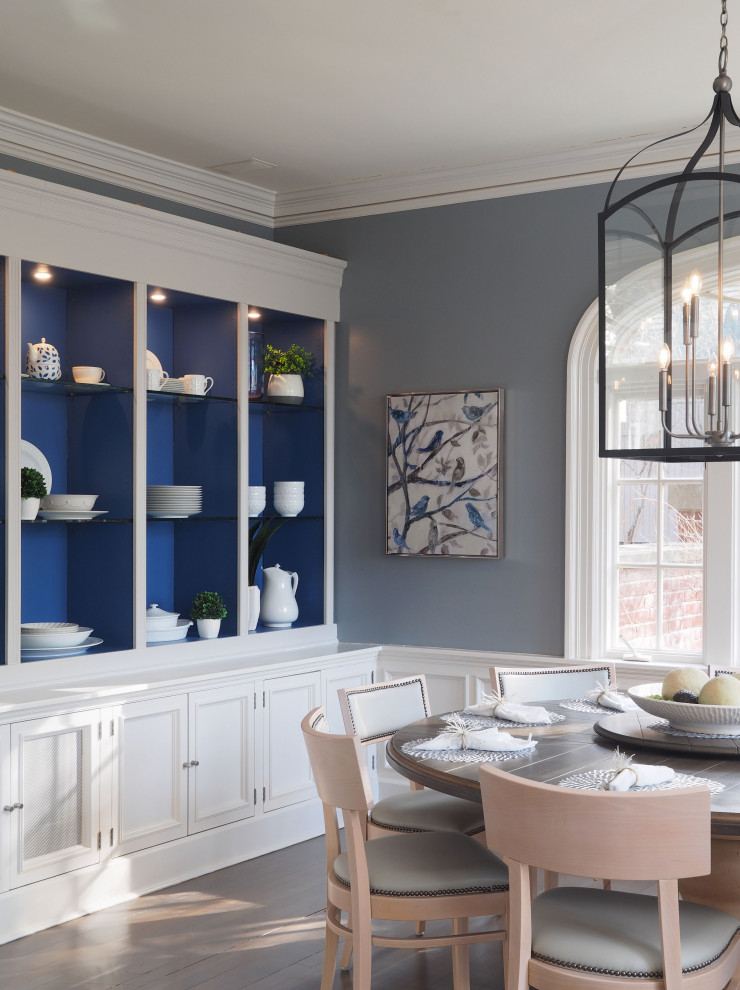 This is an example of a transitional separate dining room in New York with blue walls, medium hardwood floors, no fireplace, brown floor and panelled walls.