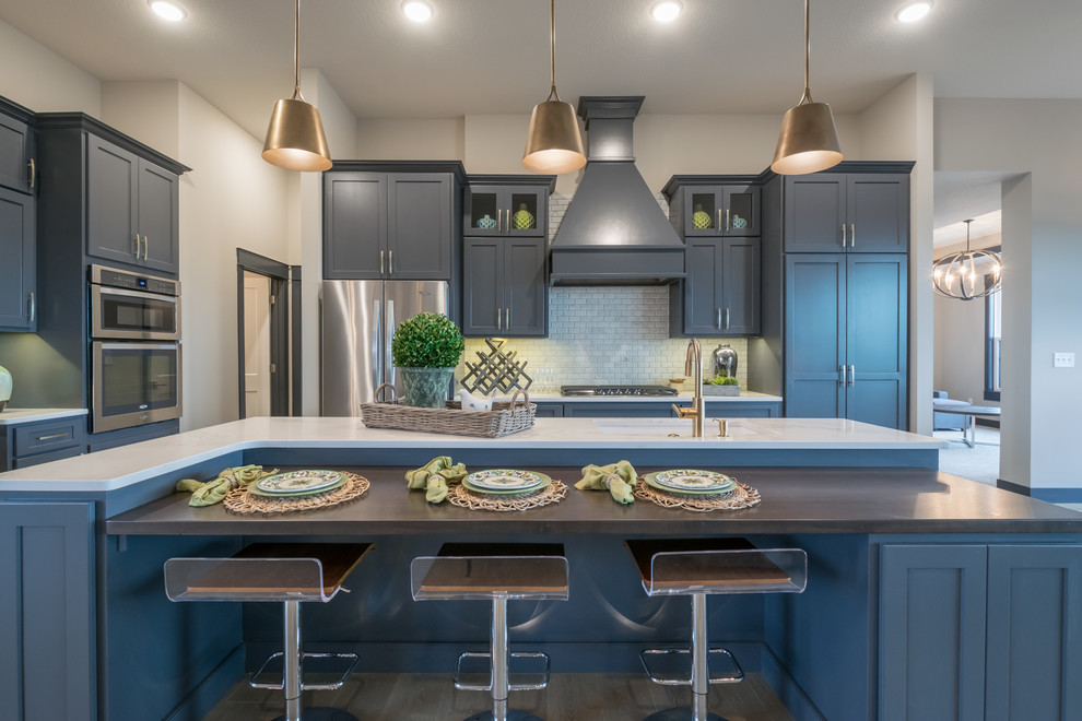 This is an example of a mid-sized transitional kitchen in Other with an undermount sink, recessed-panel cabinets, blue cabinets, quartzite benchtops, white splashback, cement tile splashback, stainless steel appliances, light hardwood floors, with island and beige floor.