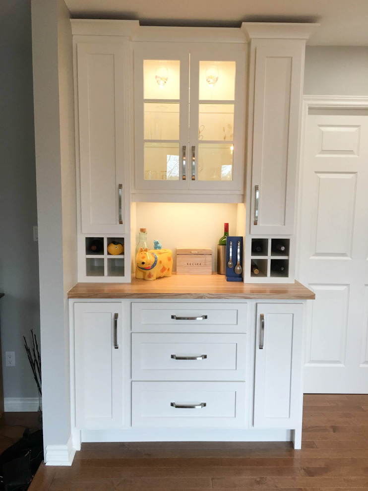 Example of a mid-sized transitional l-shaped medium tone wood floor and brown floor enclosed kitchen design with a double-bowl sink, shaker cabinets, gray cabinets, quartz countertops, white backsplash, porcelain backsplash, stainless steel appliances, an island and white countertops