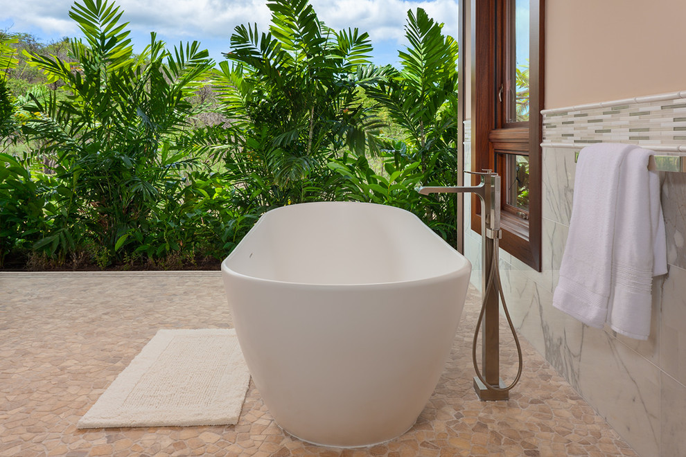 Inspiration for a large world-inspired ensuite bathroom in Hawaii with a freestanding bath, white tiles, marble tiles, white walls, pebble tile flooring and beige floors.