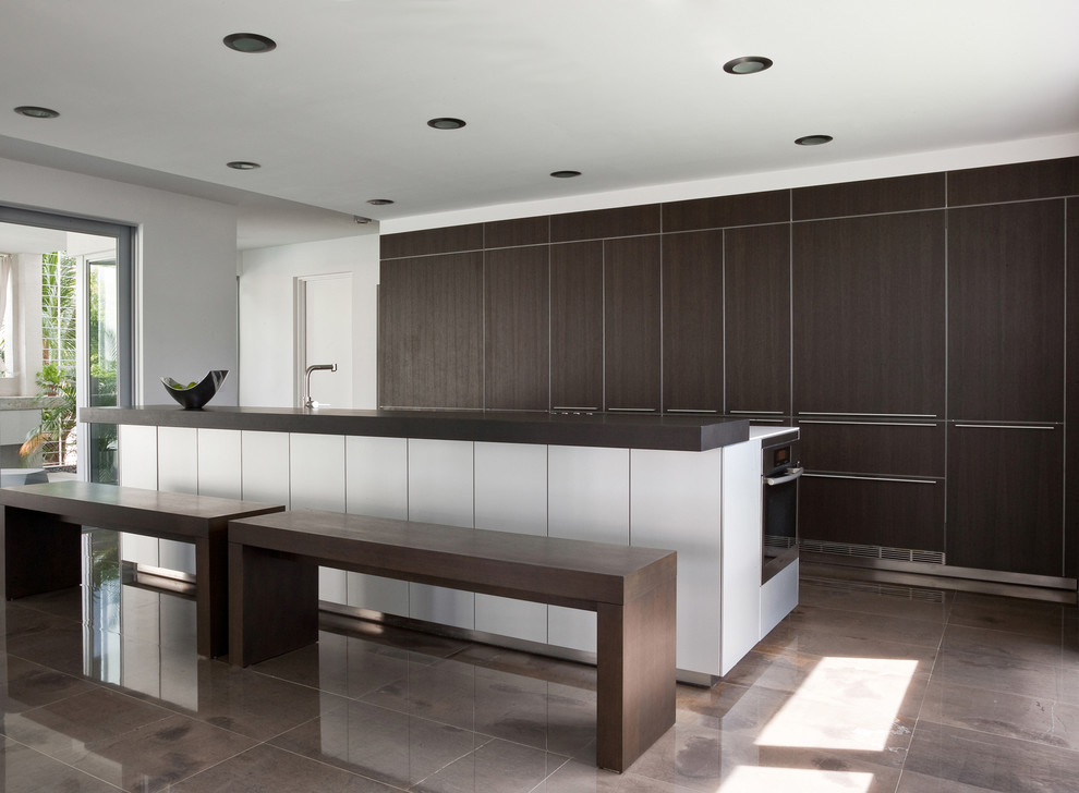 Large modern kitchen in Miami with flat-panel cabinets, dark wood cabinets, concrete floors, with island and panelled appliances.
