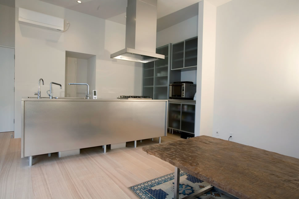 Mid-sized minimalist light wood floor and beige floor eat-in kitchen photo with glass-front cabinets, stainless steel countertops, stainless steel appliances, an island and an undermount sink