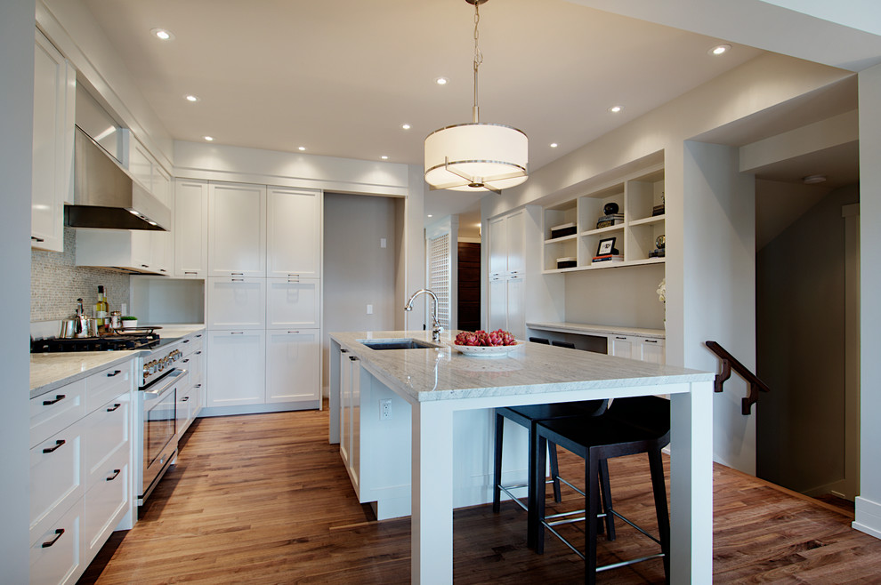 Example of a transitional l-shaped medium tone wood floor eat-in kitchen design in Calgary with an undermount sink, shaker cabinets, white cabinets, granite countertops, multicolored backsplash, glass tile backsplash, stainless steel appliances and an island