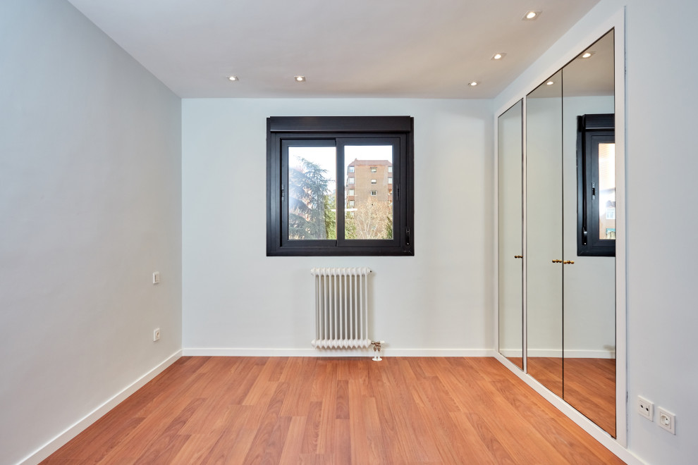 Diseño de dormitorio principal tradicional renovado grande con paredes grises y suelo de madera en tonos medios