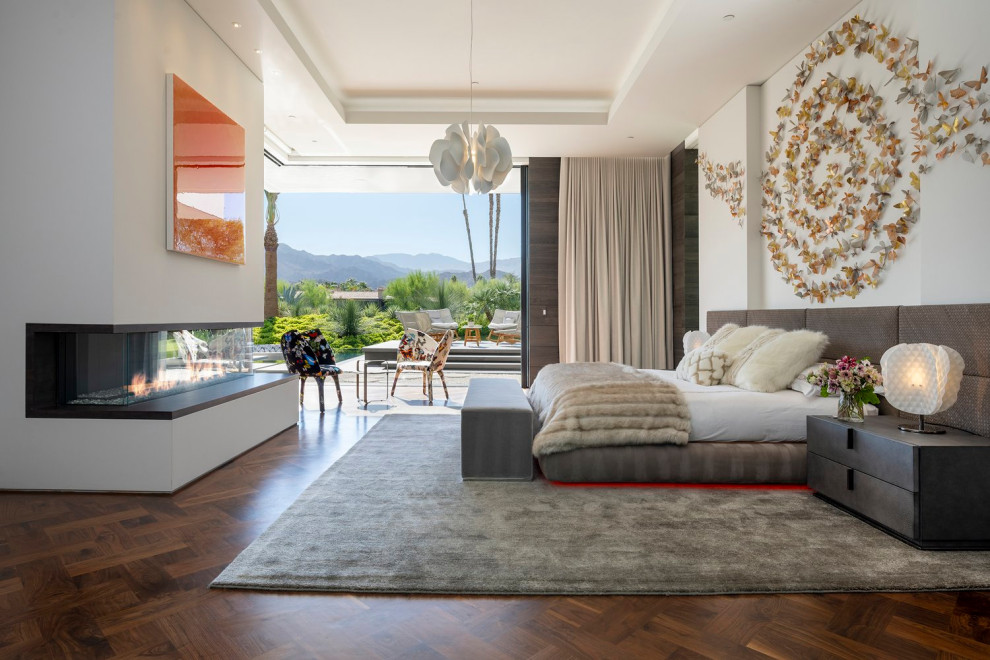 Inspiration for a huge modern master medium tone wood floor, brown floor and tray ceiling bedroom remodel in Los Angeles with white walls and a standard fireplace