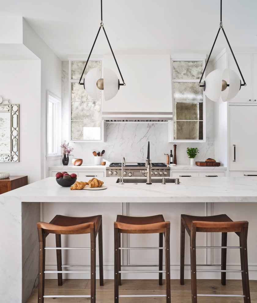 Design ideas for a contemporary galley kitchen in San Francisco with an undermount sink, flat-panel cabinets, white cabinets, white splashback, stone slab splashback, medium hardwood floors, with island, brown floor and white benchtop.