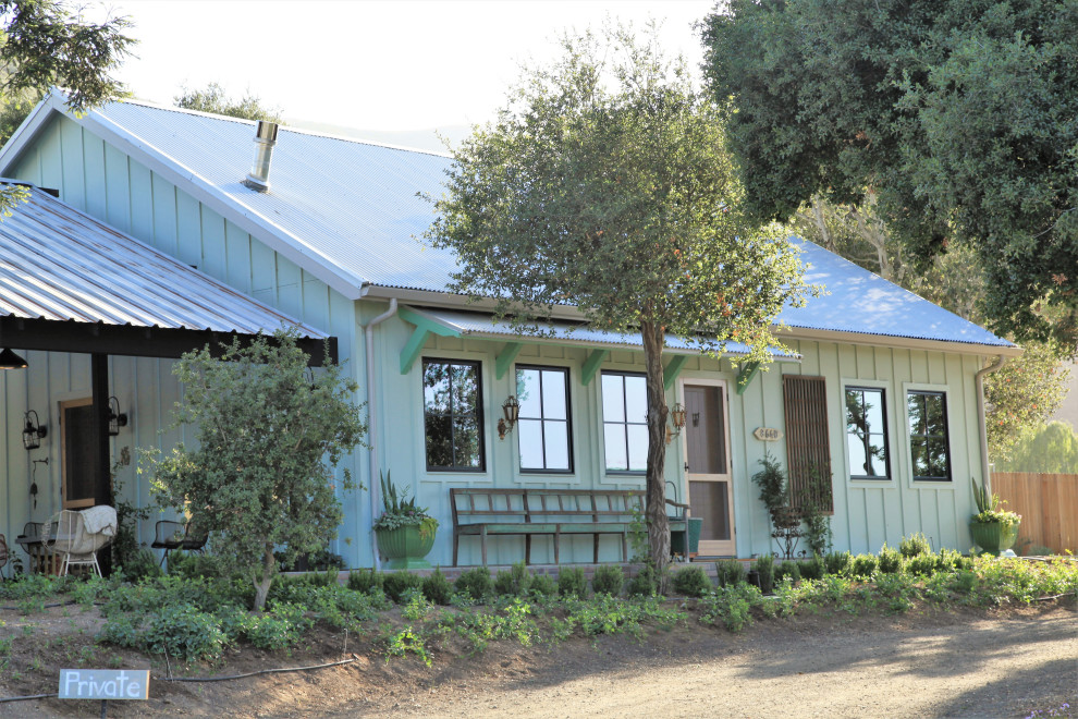 Exemple d'une façade de maison nature en bois et planches et couvre-joints avec un toit en métal et un toit gris.