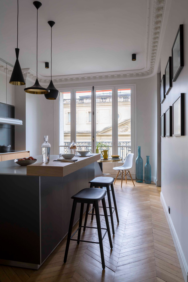 Inspiration for a large contemporary single-wall separate kitchen in Paris with an undermount sink, flat-panel cabinets, light wood cabinets, grey splashback, panelled appliances, light hardwood floors, with island, beige floor and white benchtop.