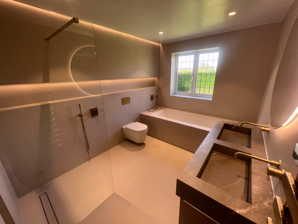This is an example of a small kids wet room bathroom in Hertfordshire with grey cabinets, a drop-in tub, a wall-mount toilet, grey walls, concrete floors, tile benchtops, an open shower, a double vanity and a floating vanity.