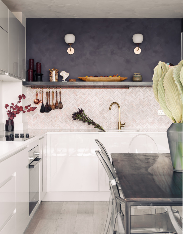 Inspiration for a small contemporary l-shaped kitchen/diner in Other with a built-in sink, flat-panel cabinets, white cabinets, composite countertops, ceramic splashback, integrated appliances, laminate floors and white worktops.