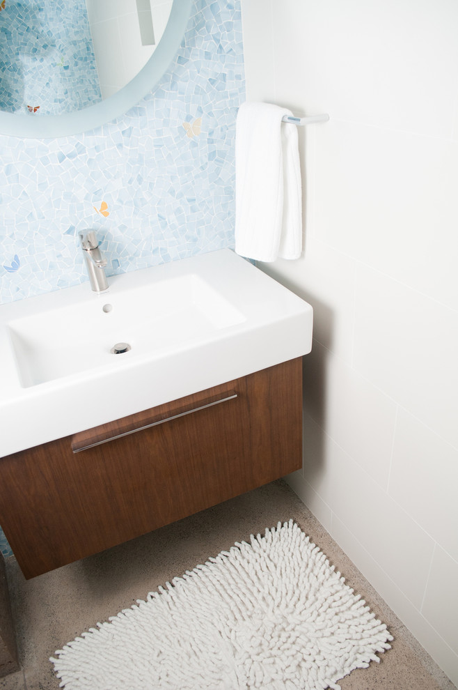 Cette image montre une salle de bain minimaliste en bois brun pour enfant avec un placard à porte plane, un carrelage bleu, mosaïque, un mur blanc, un sol en terrazzo, un lavabo intégré, un sol beige, meuble simple vasque et meuble-lavabo suspendu.