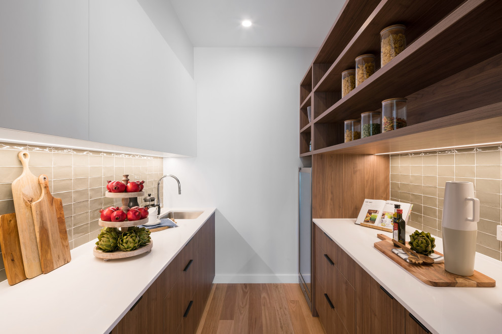 Large contemporary galley kitchen pantry in Brisbane with medium wood cabinets, quartz benchtops, ceramic splashback, white benchtop, an undermount sink, flat-panel cabinets, grey splashback, medium hardwood floors, no island and brown floor.