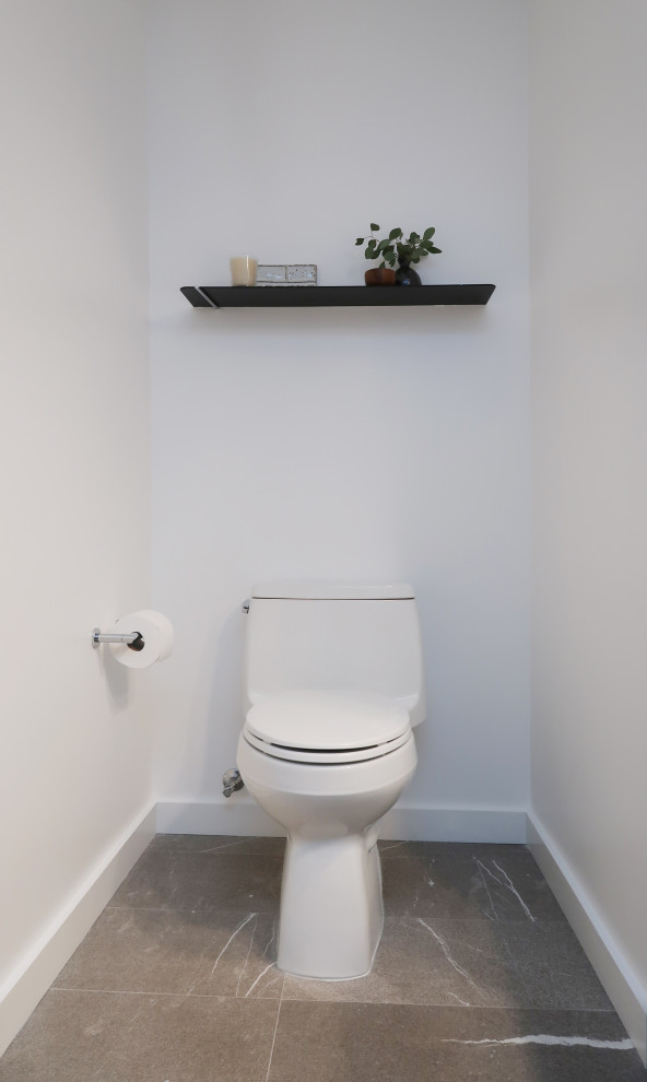 Réalisation d'un WC et toilettes en bois clair de taille moyenne avec un placard à porte plane, WC à poser, un carrelage blanc, un carrelage de pierre, un mur blanc, une vasque, un plan de toilette en quartz modifié, un sol gris, un plan de toilette blanc et meuble-lavabo suspendu.