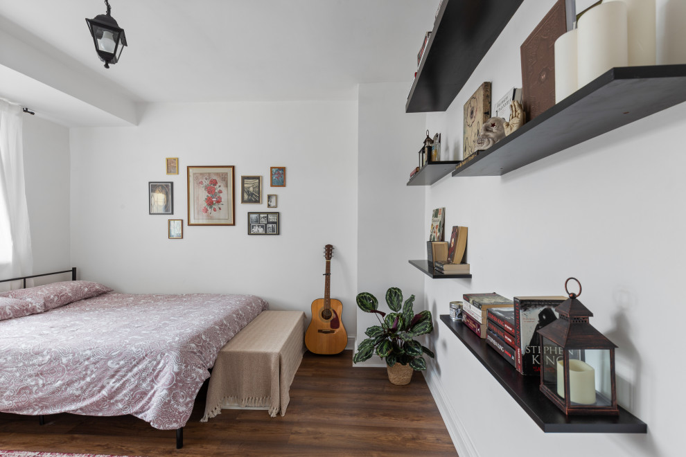 Immagine di una camera matrimoniale minimal di medie dimensioni con pareti bianche, pavimento in laminato e pavimento marrone