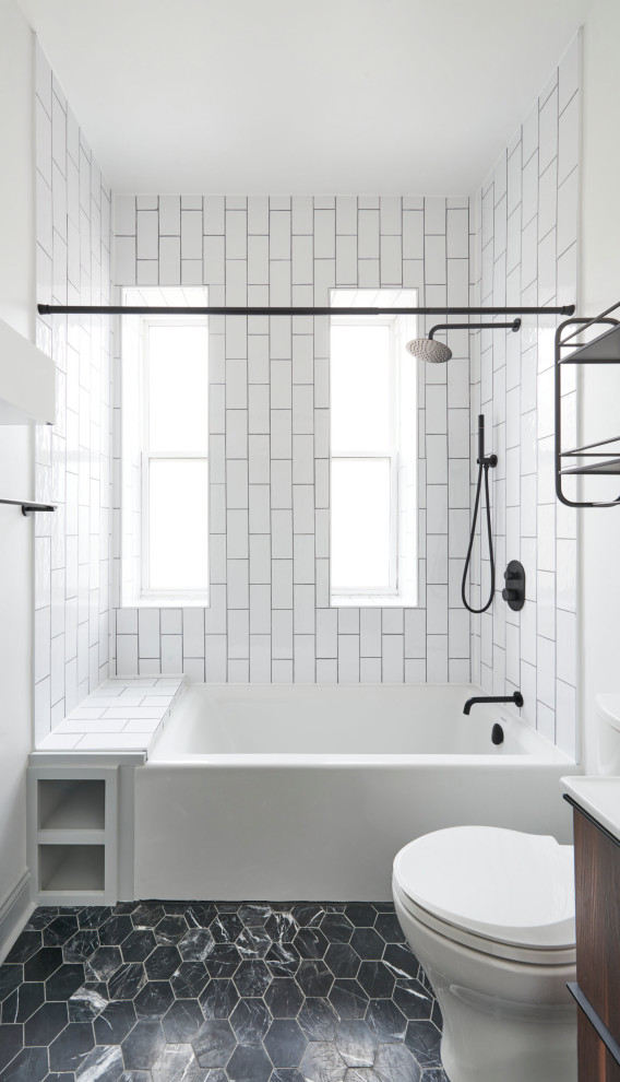 Idéer för att renovera ett litet vintage vit vitt en-suite badrum, med släta luckor, bruna skåp, ett badkar i en alkov, en dusch/badkar-kombination, en toalettstol med separat cisternkåpa, vit kakel, vita väggar, klinkergolv i porslin och svart golv