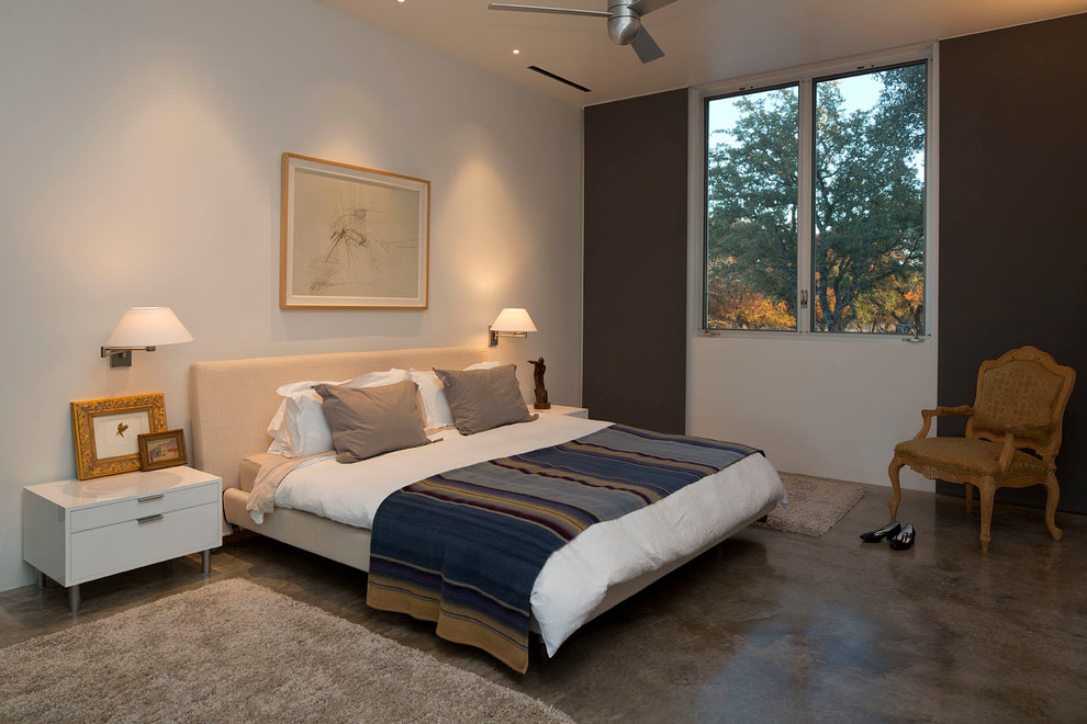 This is an example of a large contemporary guest bedroom in Austin with concrete floors, white walls and no fireplace.