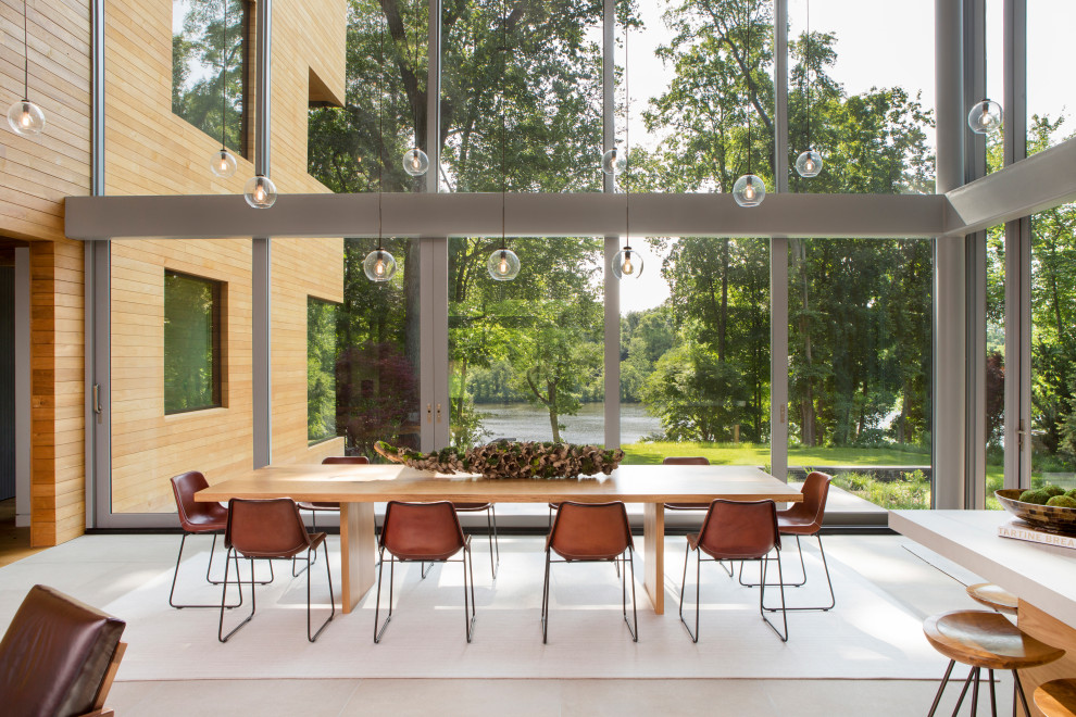 На фото: большая гостиная-столовая в стиле модернизм с полом из известняка, серым полом, деревянными стенами и бежевыми стенами без камина
