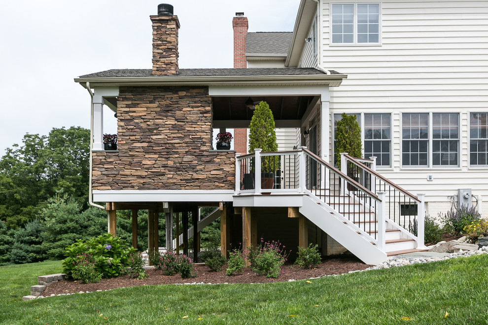 Large traditional backyard deck in Baltimore with a fire feature and a roof extension.