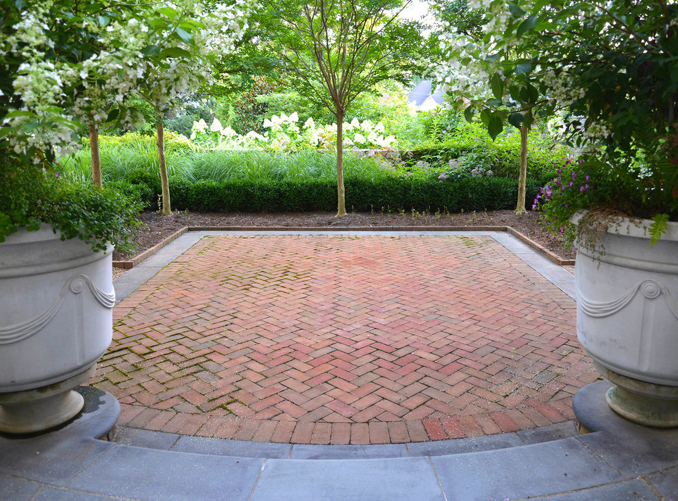 This is an example of a mid-sized traditional backyard patio in DC Metro with no cover and brick pavers.