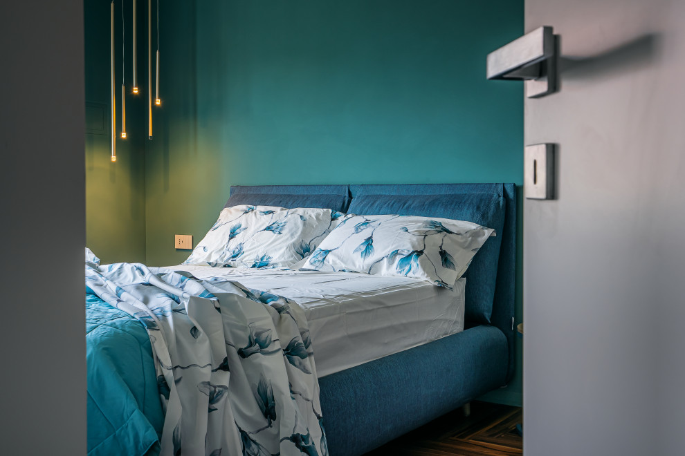 This is an example of a scandi master bedroom in Rome with blue walls and dark hardwood flooring.