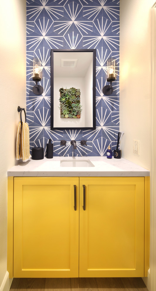 Идея дизайна: маленький туалет в стиле неоклассика (современная классика) с фасадами в стиле шейкер, желтыми фасадами, синей плиткой, керамогранитной плиткой, белыми стенами, врезной раковиной, столешницей из искусственного кварца, серым полом, белой столешницей и встроенной тумбой для на участке и в саду