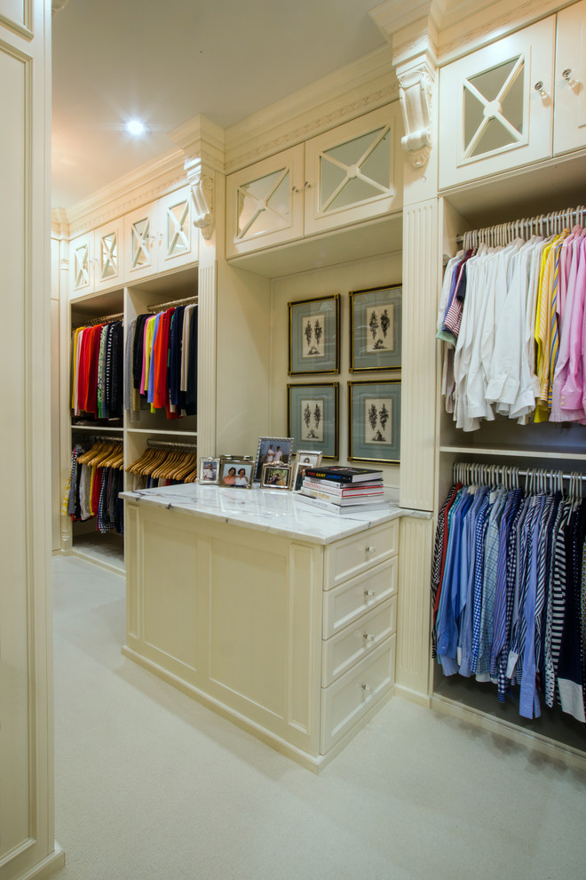 Photo of a large transitional gender-neutral walk-in wardrobe in Charlotte with recessed-panel cabinets, white cabinets, carpet and beige floor.