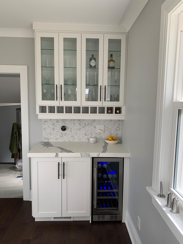 Design ideas for a small contemporary single-wall home bar in Other with no sink, shaker cabinets, white cabinets, solid surface benchtops, grey splashback, mosaic tile splashback, medium hardwood floors, brown floor and white benchtop.