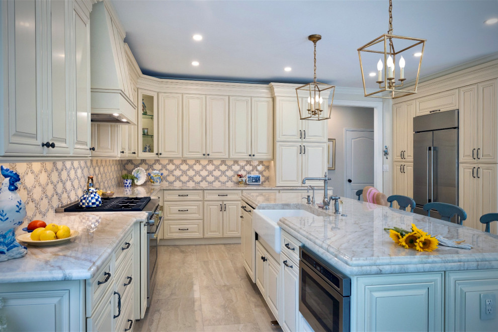 Example of a large transitional l-shaped porcelain tile, beige floor and vaulted ceiling eat-in kitchen design in Philadelphia with a farmhouse sink, raised-panel cabinets, yellow cabinets, quartzite countertops, yellow backsplash, ceramic backsplash, stainless steel appliances, an island and beige countertops