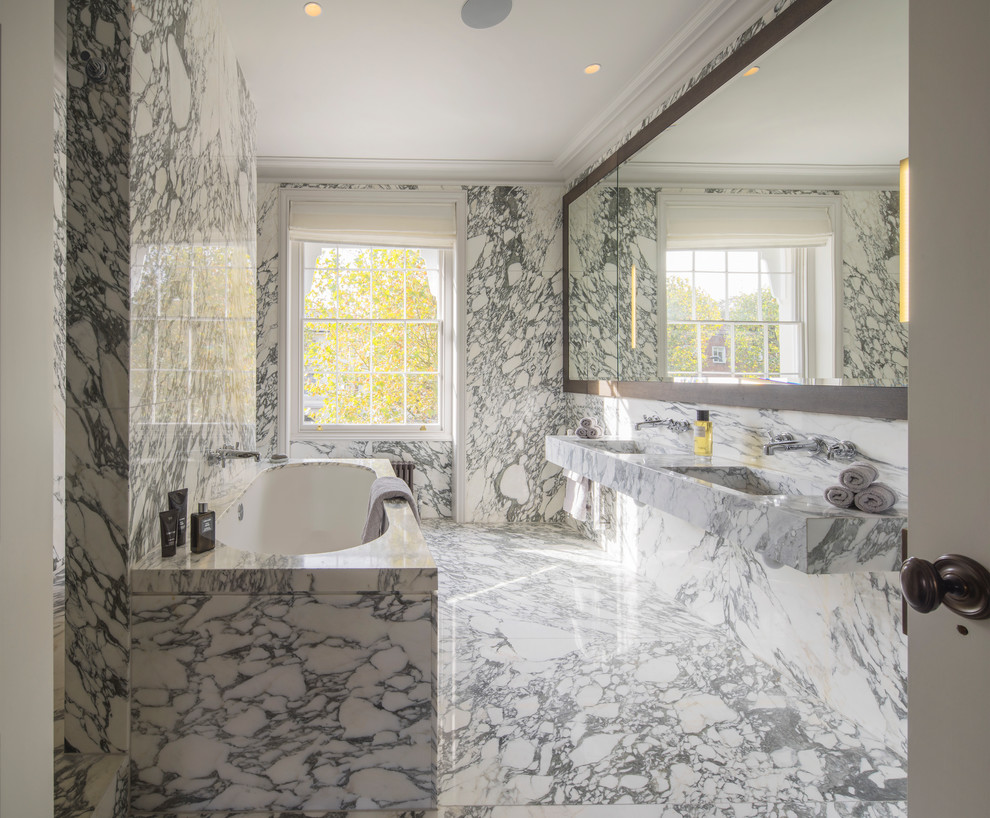 Inspiration for a large traditional master bathroom in London with a drop-in tub, an open shower, a wall-mount toilet, white tile, stone tile, white walls, marble floors, a trough sink and marble benchtops.
