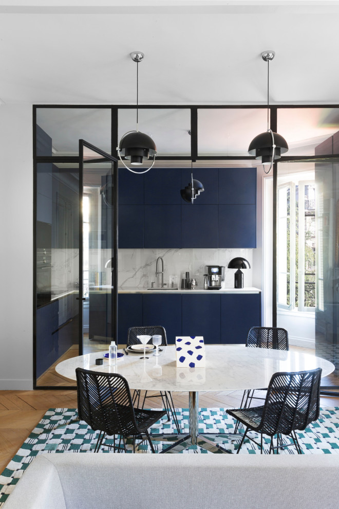 Photo of a mid-sized contemporary l-shaped kitchen in Paris with an integrated sink, blue cabinets, marble benchtops, white splashback, marble splashback, black appliances, light hardwood floors, no island and white benchtop.