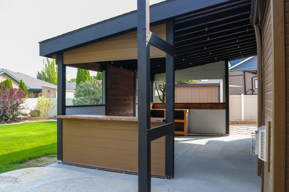 Ispirazione per un patio o portico american style di medie dimensioni e dietro casa con lastre di cemento e un tetto a sbalzo