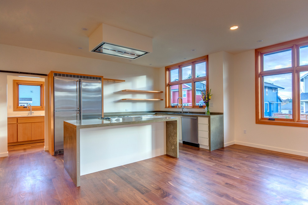 Mid-sized modern l-shaped open plan kitchen in Portland with an undermount sink, flat-panel cabinets, white cabinets, concrete benchtops, stainless steel appliances, medium hardwood floors and with island.