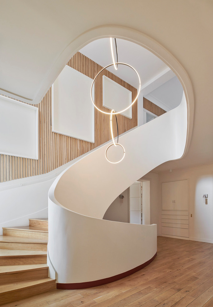 Идея дизайна: большая изогнутая деревянная лестница в современном стиле с деревянными ступенями, перилами из смешанных материалов и деревянными стенами